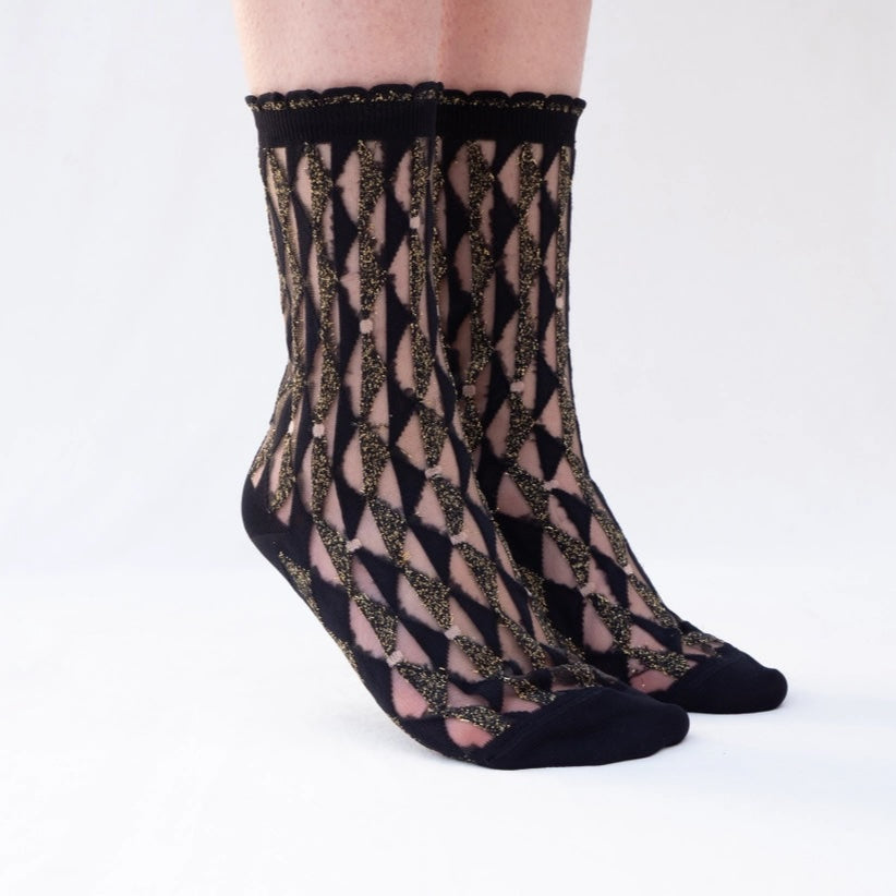 Sheer socks with a geometric pattern worn by a person on a white background