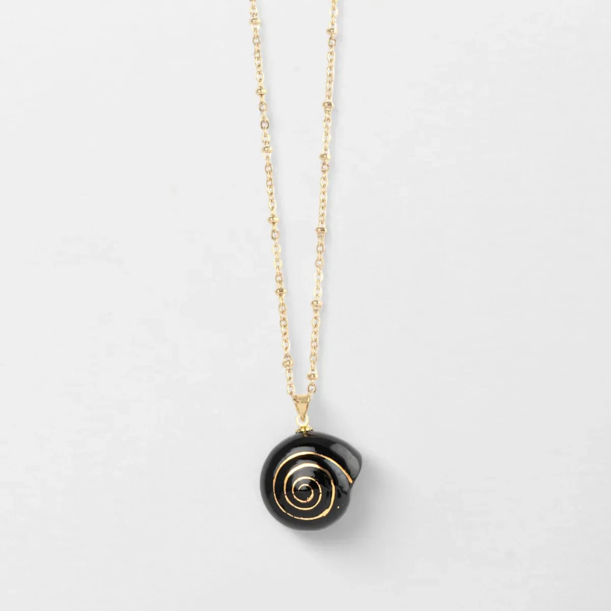 Black spiral pendant necklace on a thin chain against a light gray background