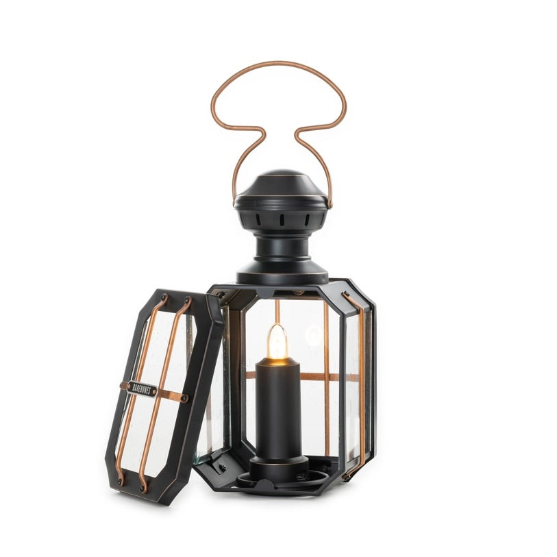 Black lantern with a lit candle inside on a white background