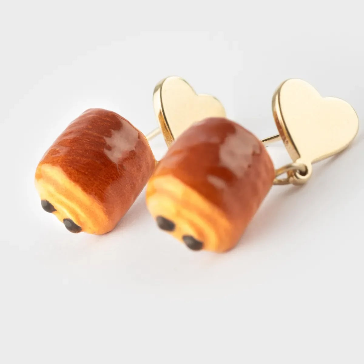 Bread-shaped earrings with gold heart backs on a light gray background