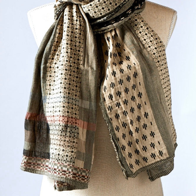 A beige and patterned scarf displayed on a mannequin.
