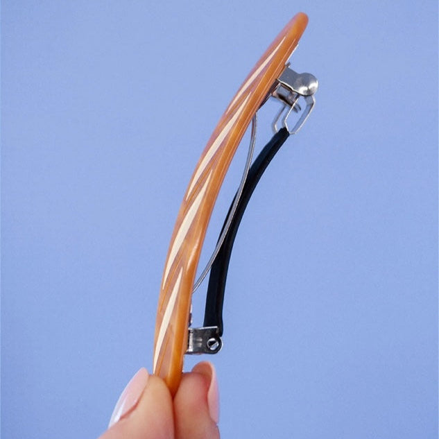 Hair straightener held by a hand against a blue background
