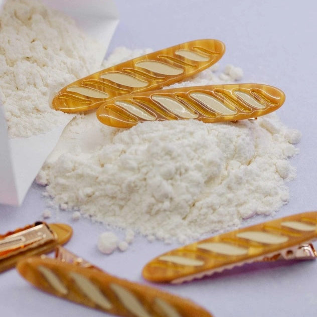 White flour with gold-colored baguette hair clips on a white background