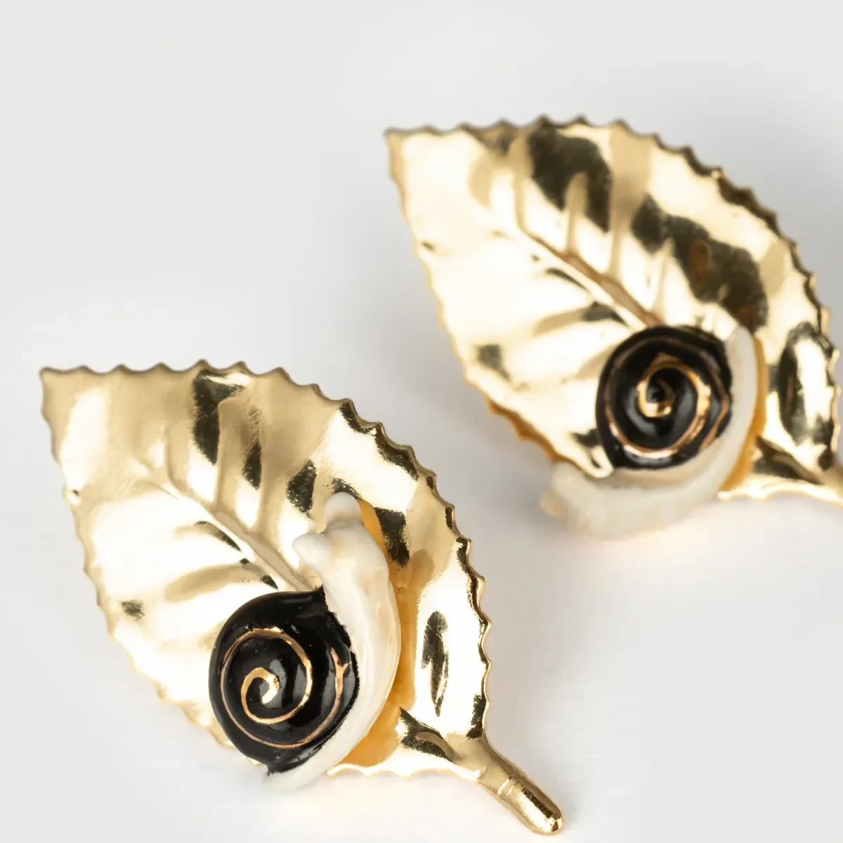Gold leaf-shaped earrings on a light gray background