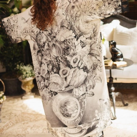 Woman in a floral dress standing in an elegant room with decorative elements.