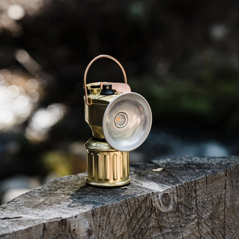 Vintage-style camping lantern on a wooden post with a blurred natural background