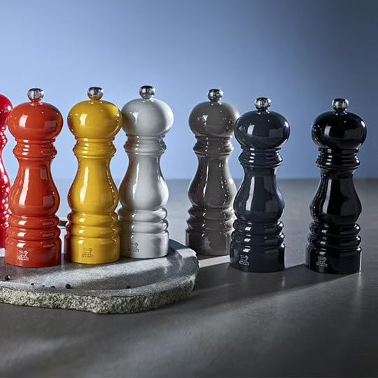 Set of colorful pepper mills on a gray surface with a blue gradient background