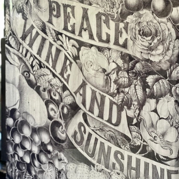 printed scarf with fruits, flowers, and text 'Peace Wine and Sunshine' on a textured background.