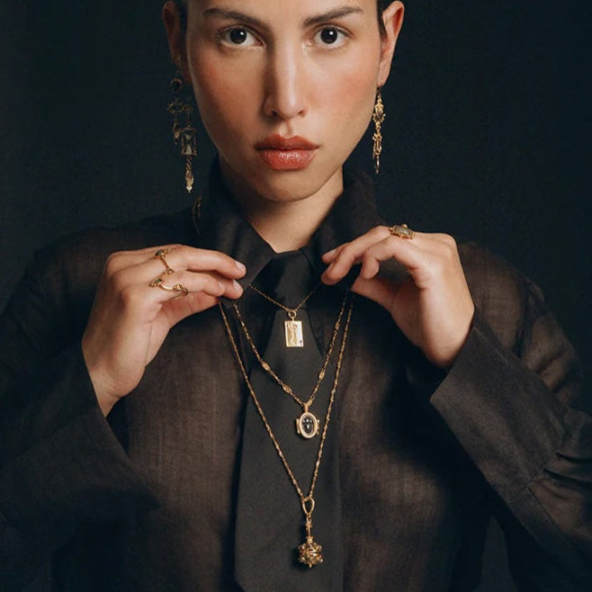 Woman wearing gold jewelry against a dark background