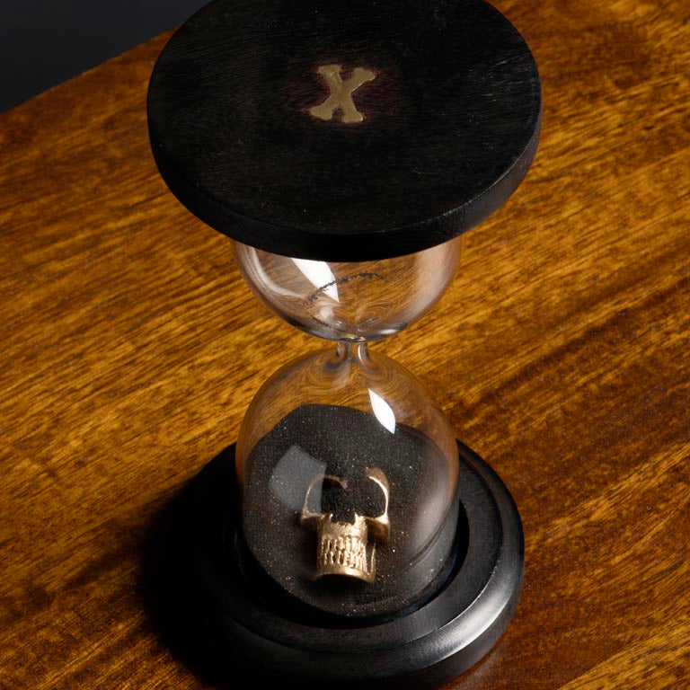 Hourglass with a gold skull on a wooden surface