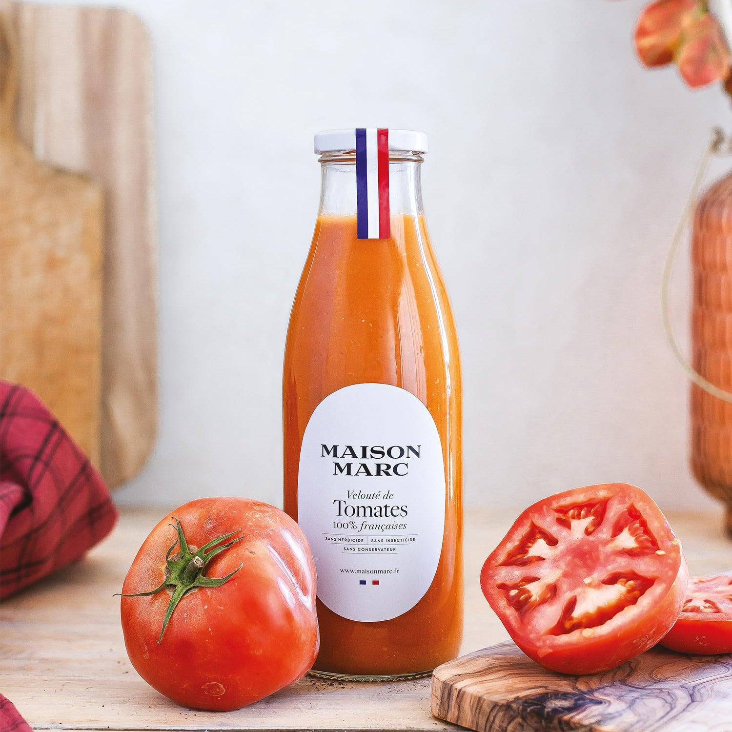 Bottle of Maison Marc tomato juice with fresh tomatoes on a wooden surface