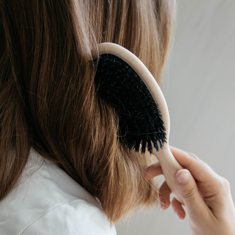 Woman brushing long hair with the pale beech and black boar bristle brush – Andrée Jardin