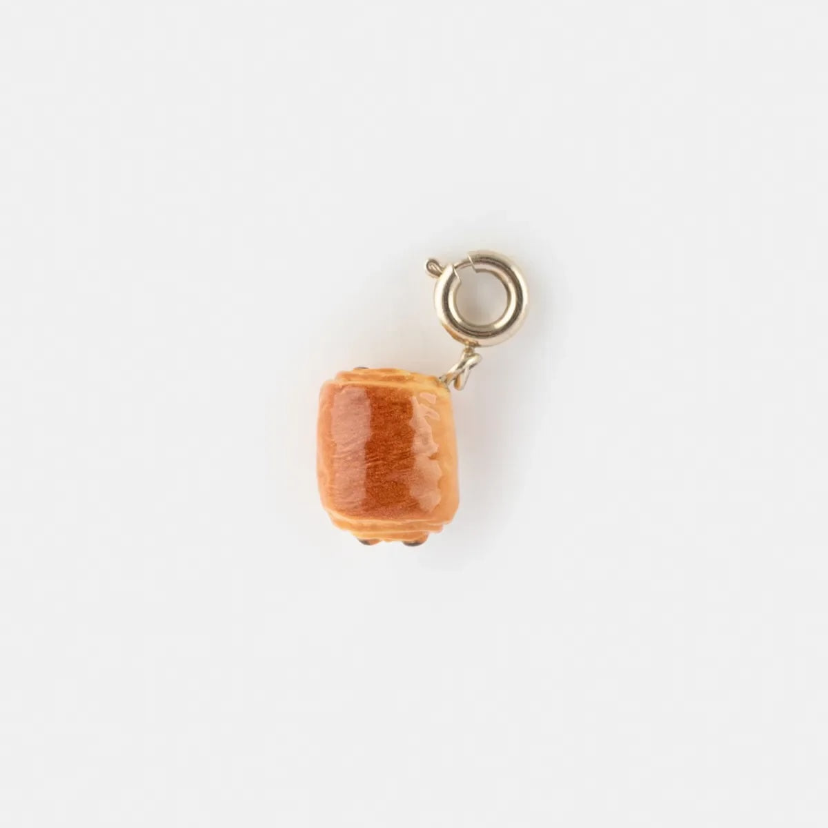 Gold charm with a chocolatine shaped porcelain on a white background