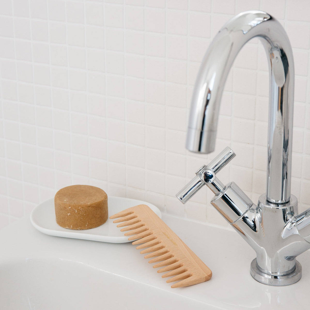 The beech comb resting beside a chrome basin tap and a soap dish – Andrée Jardin
