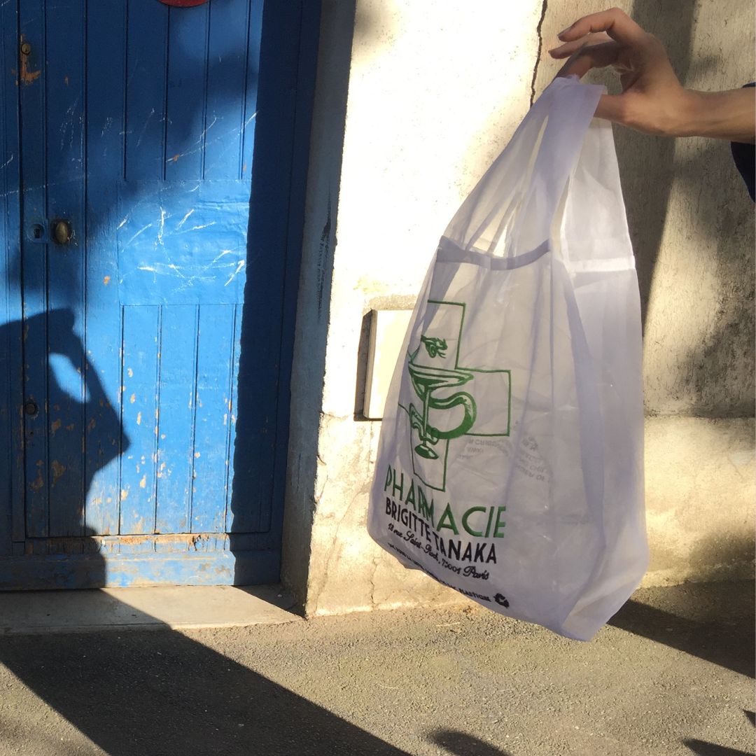 Hand holding the translucent Pharmacie organza bag against a blue door – Brigitte Tanaka