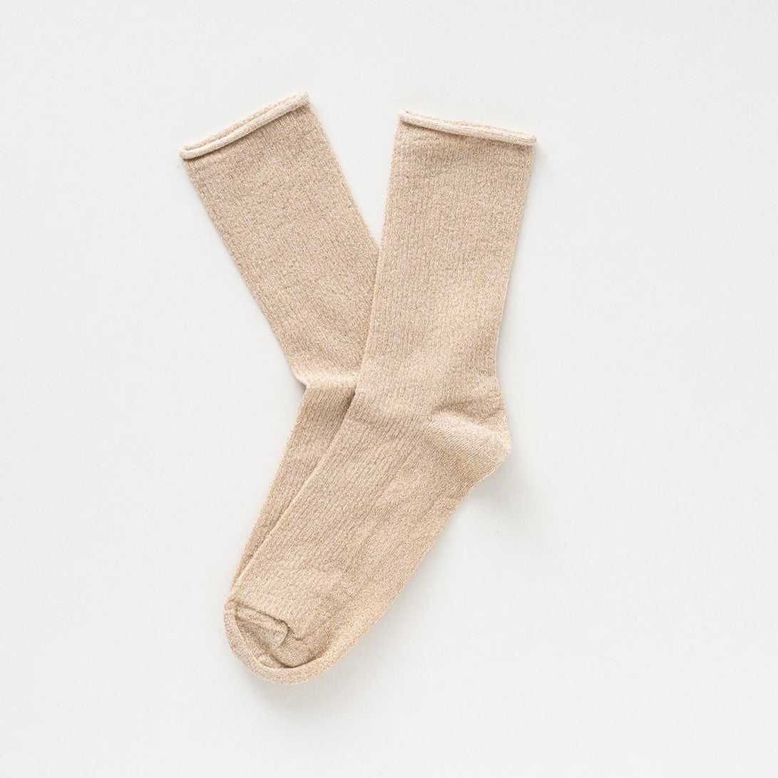 Pale beige socks with a golden lurex shimmer, laid flat to show the rolled cuffs – KLUE