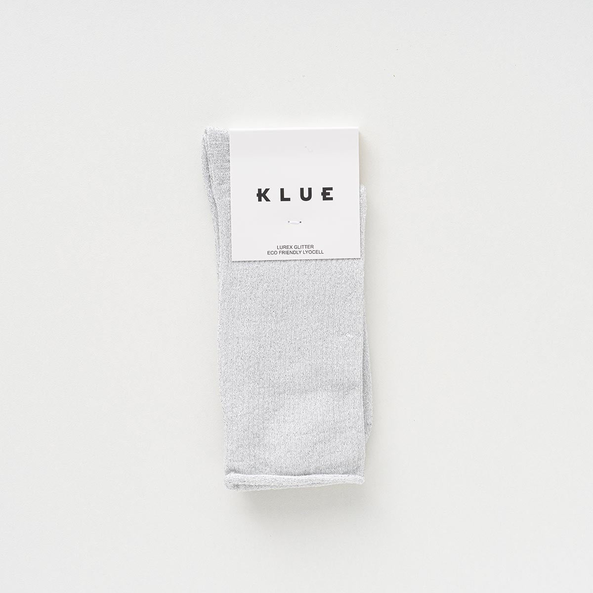 Folded pair of white socks with a fine silver glitter in a KLUE paper band – KLUE