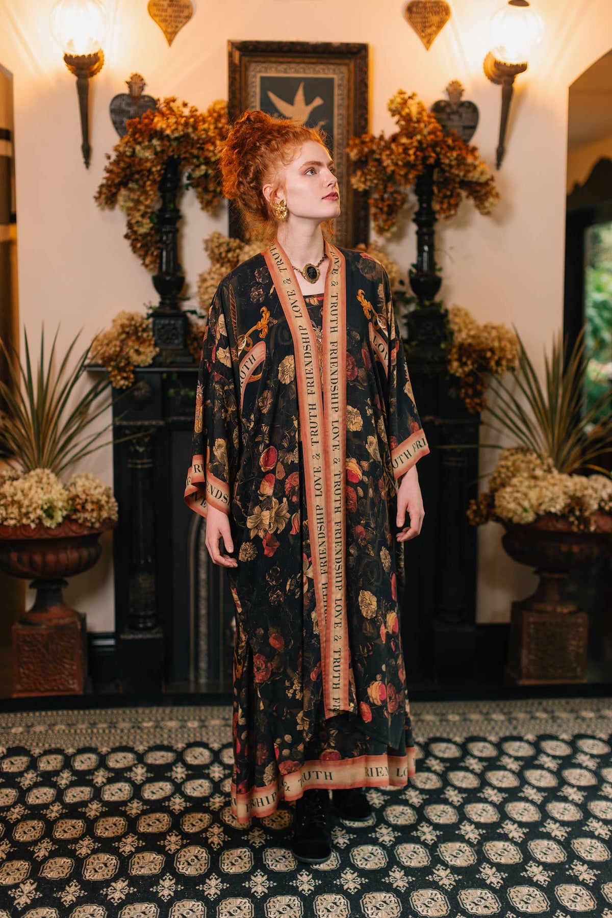 Red-haired woman wearing a long black kimono with red roses and gold lettered trim – Market of Stars