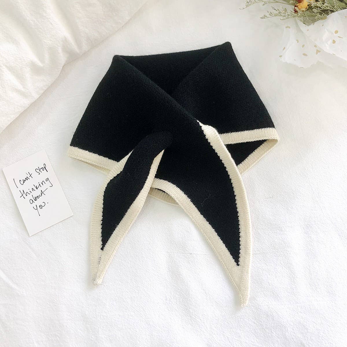 Black knitted triangle neck scarf with cream contrast trim and pointed tails, laid flat on white linen – ACCITY
