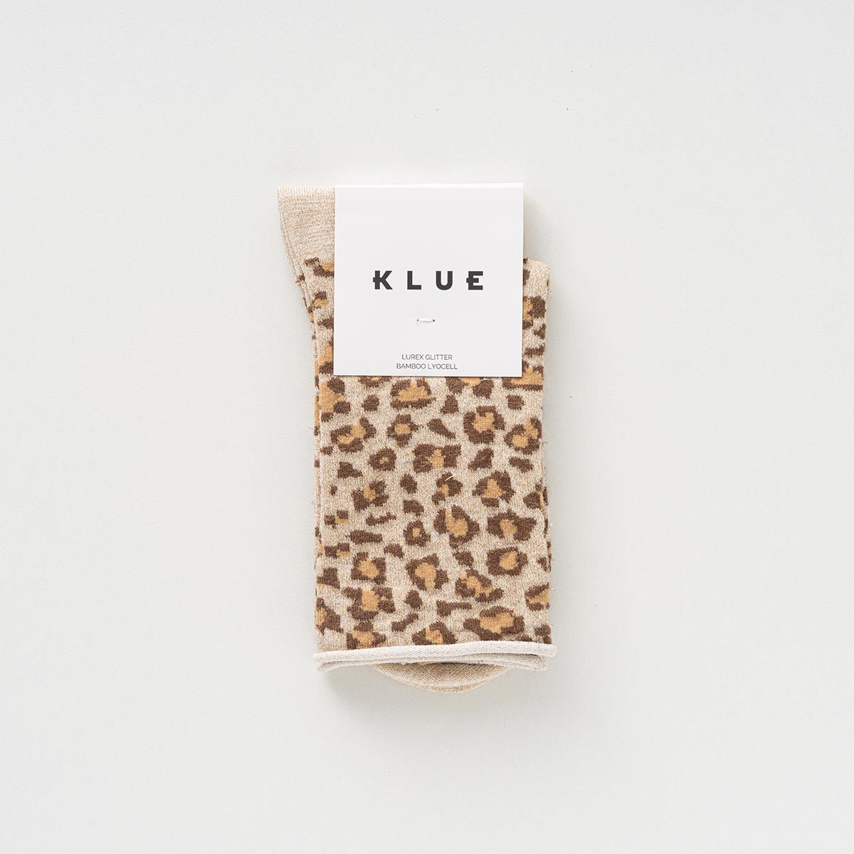 Folded pair of cream and caramel leopard-print socks with glitter in a KLUE paper band – KLUE
