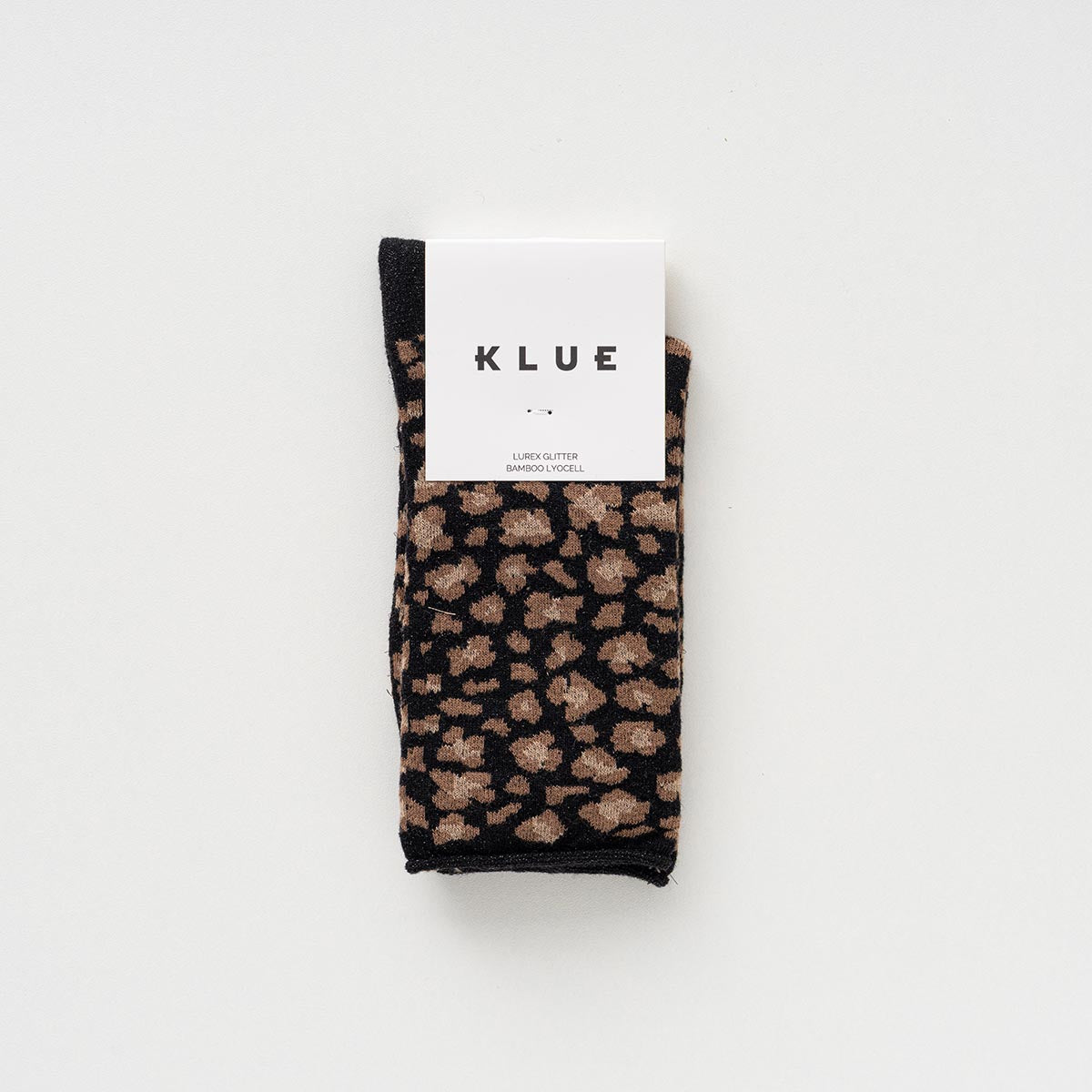 Folded pair of black and camel leopard-print socks with glitter in a KLUE paper band – KLUE