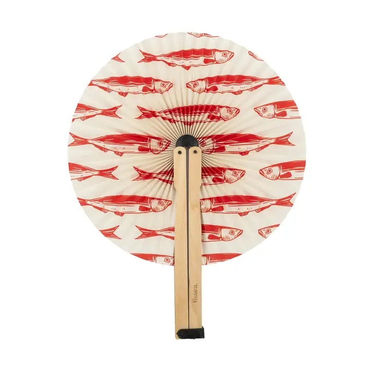 A round folding hand fan with a cream-colored paper surface printed with a repeating red fish pattern, attached to a light natural wood handle with black plastic end caps, shown against a plain white background.