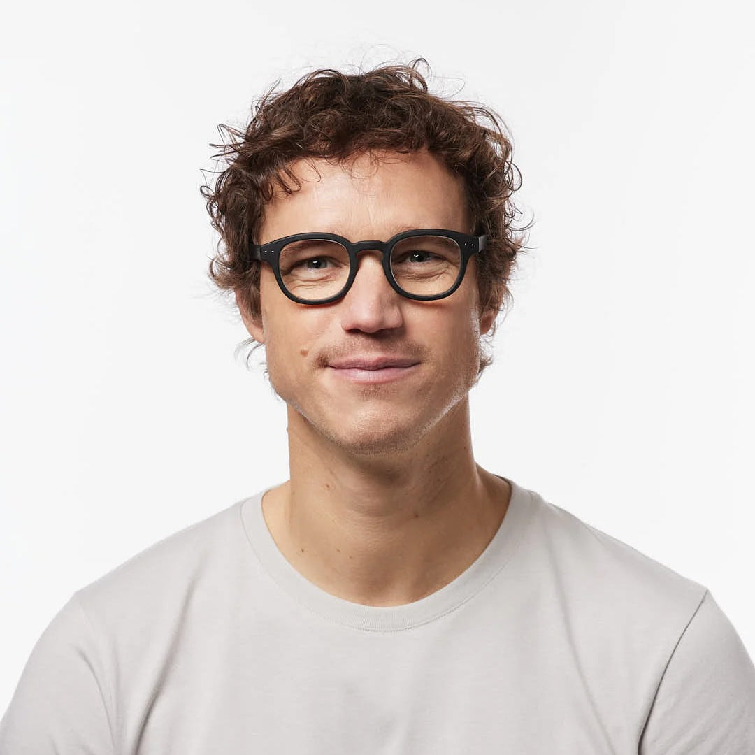 Man wearing glasses and a light gray shirt on a white background