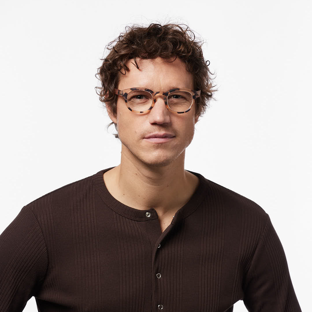 Man wearing glasses and a brown long-sleeve shirt on a white background