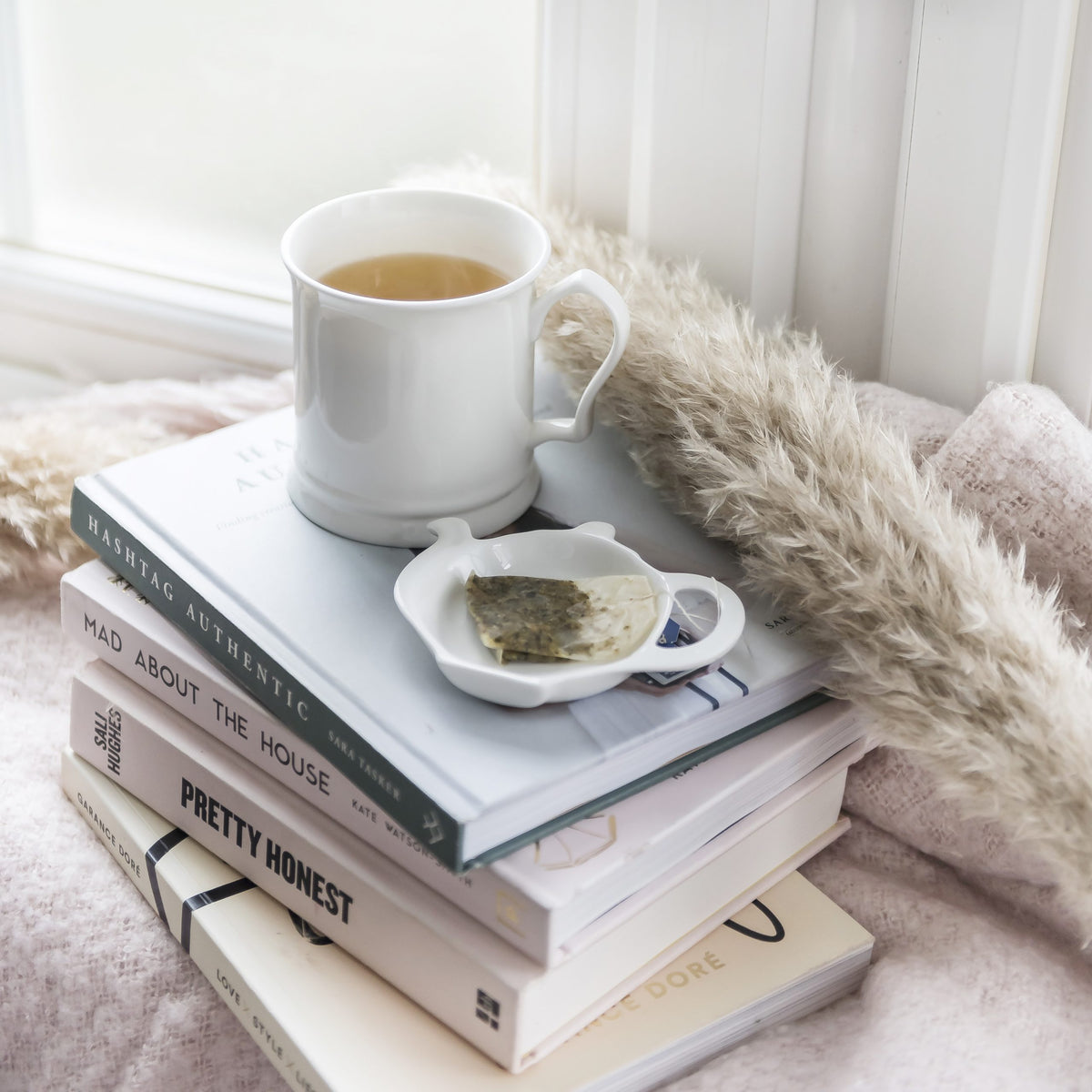 White teapot-shaped china teabag tidy holding a used teabag beside a mug of tea – Buttercup