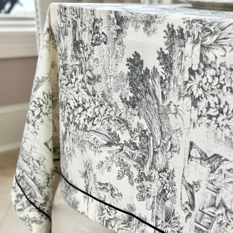 Decorative tablecloth with black and white floral pattern on a table.