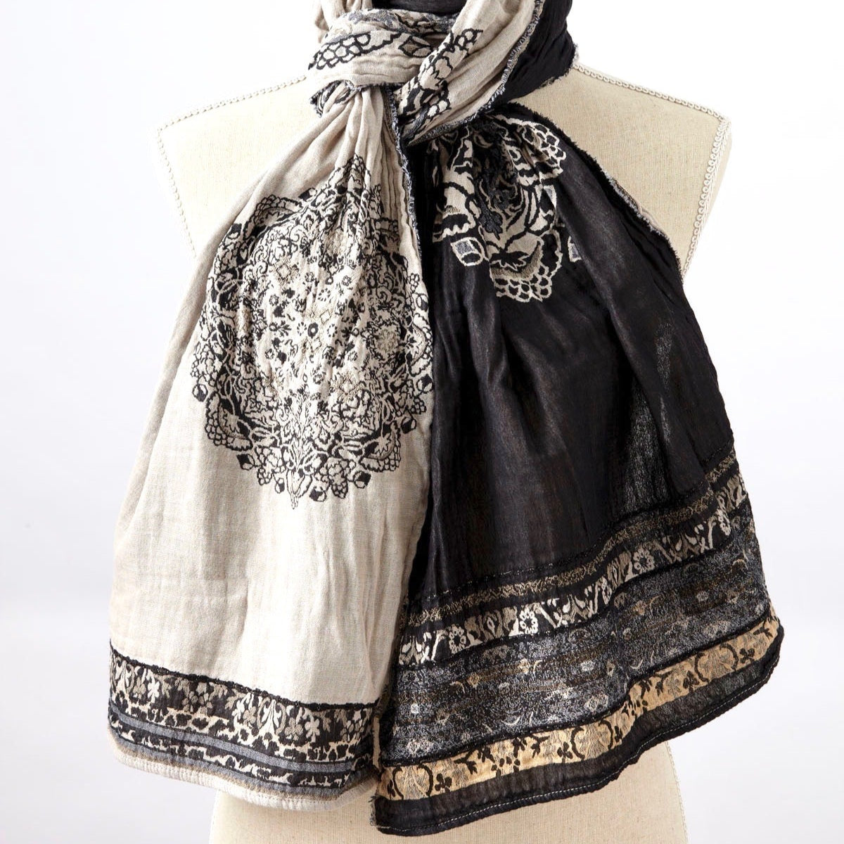 A beige and patterned scarf displayed on a mannequin.