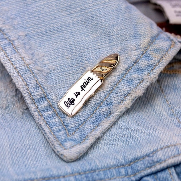 Metallic pin with 'Life is plain' text on a denim jacket
