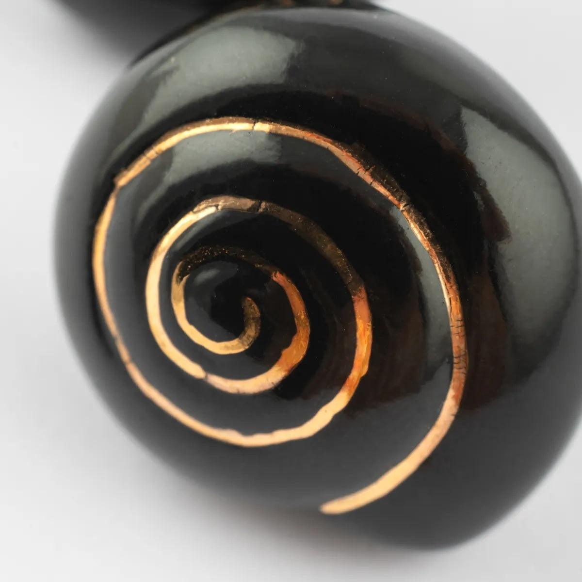 Black ceramic earrings with gold spiral designs on a white background