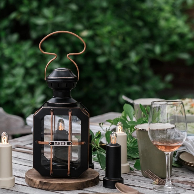 Decorative lantern on a table with candles and glasses outdoors