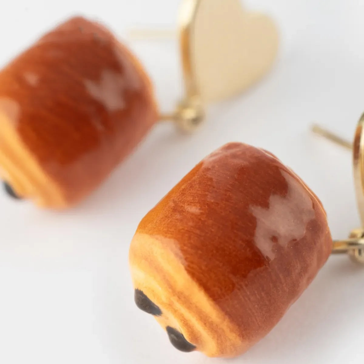 Chocolatine shaped earrings with gold accents on a white background