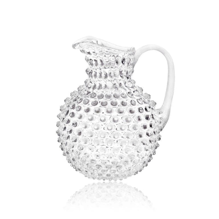Clear glass pitcher with textured surface on a white background