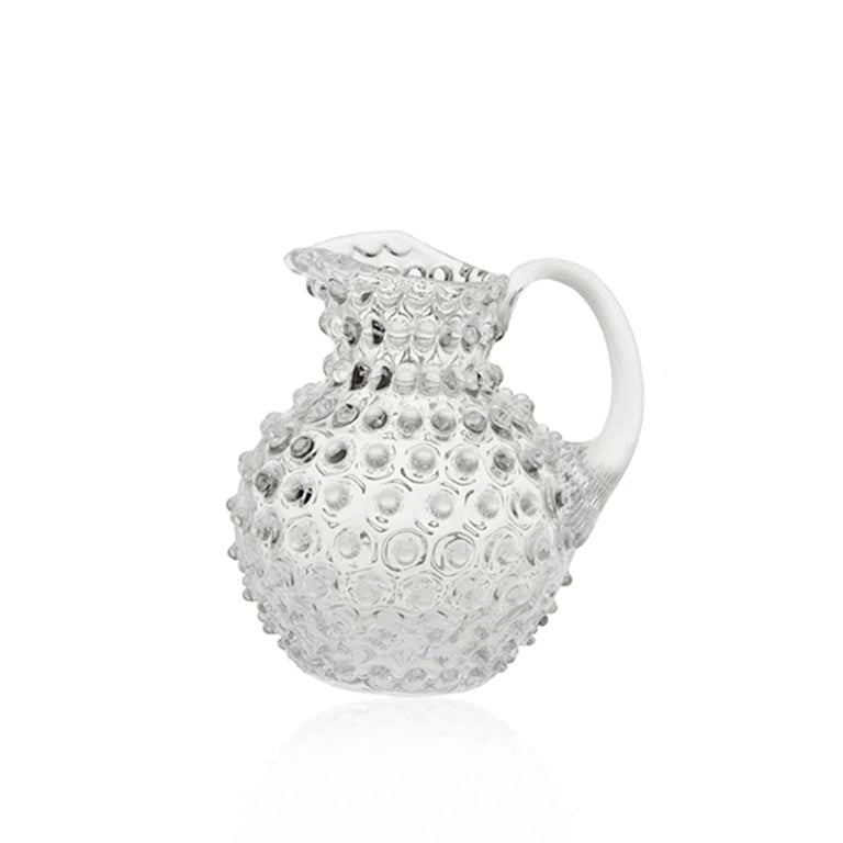 Decorative clear pitcher with textured surface on a white background