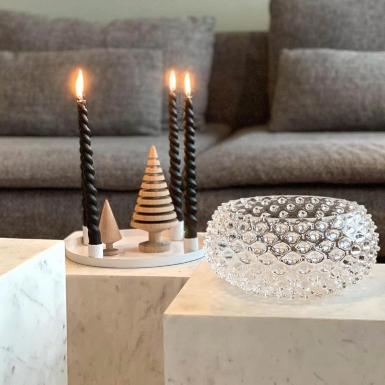 Decorative candles and a crystal bowl on a marble surface with a blurred sofa in the background