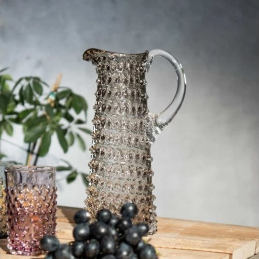 Decorative pitcher with grapes on a wooden surface