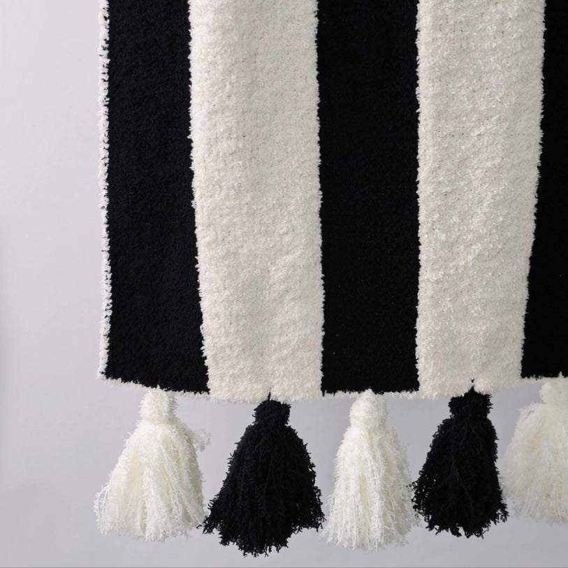 Black and white striped fabric with tassels on a light gray background