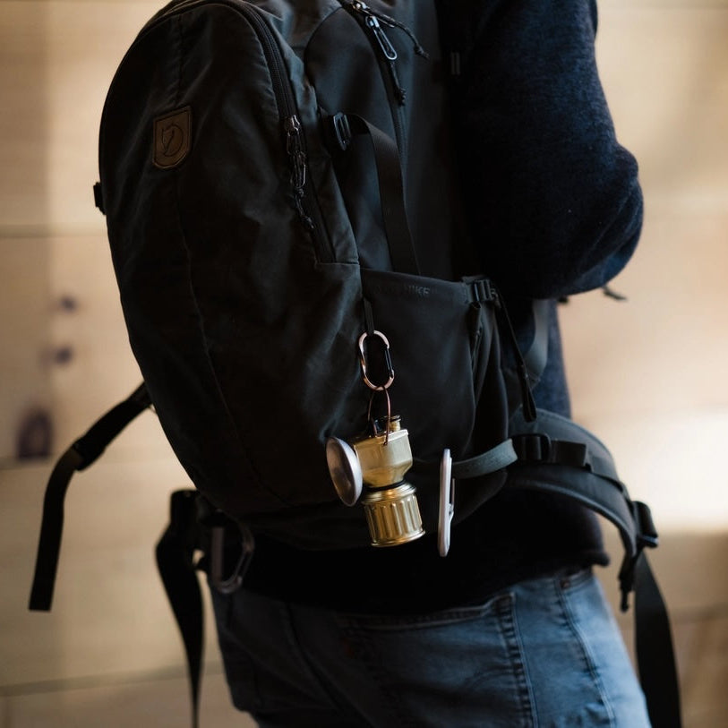 Person wearing a black backpack with a miner lantern and pen on a blurred background