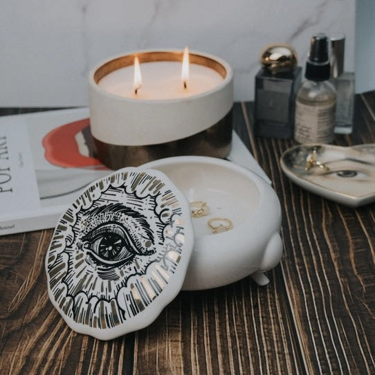 Candle in a decorative holder with a marble wall and wooden surface in the background
