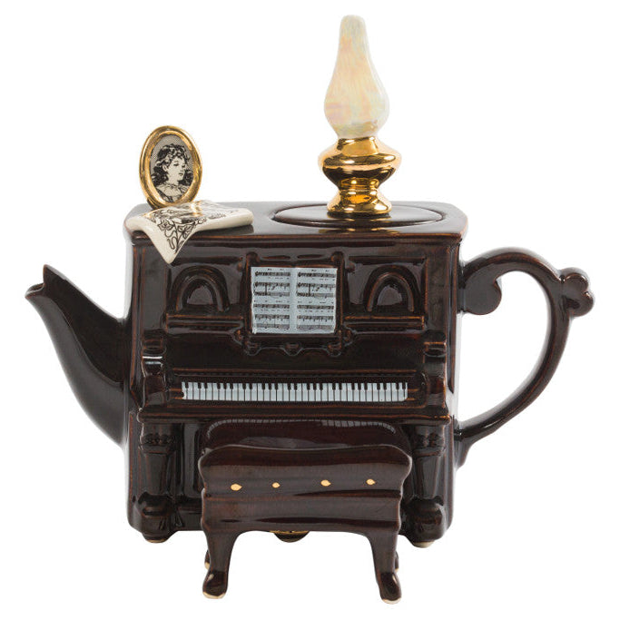 Teapot designed like a piano with a lamp on top, on a white background