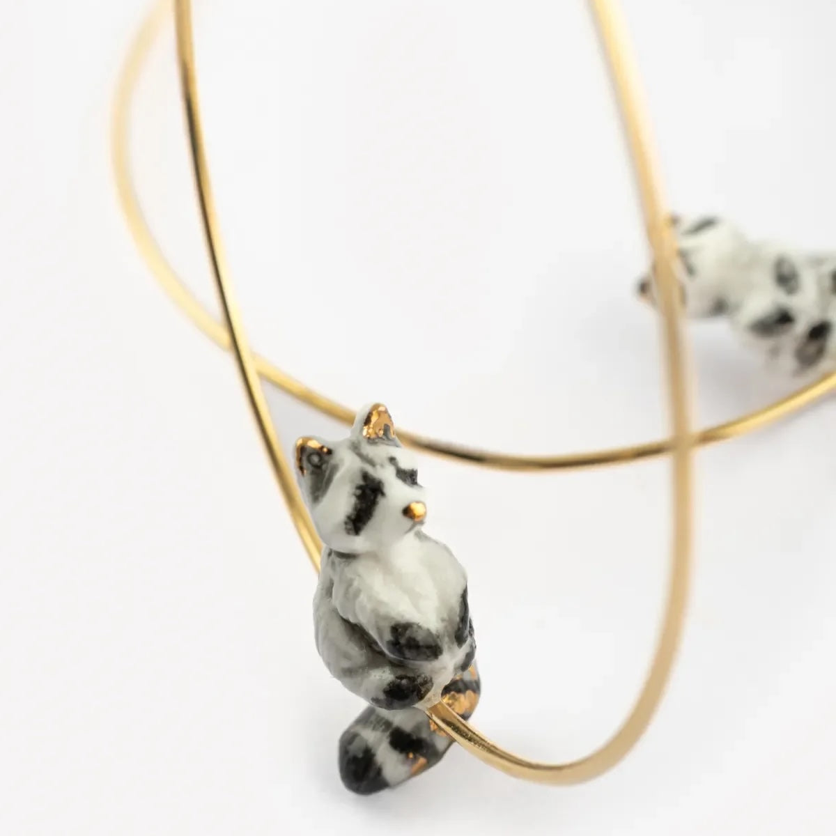 raccoon pendant on a gold chain against a white background