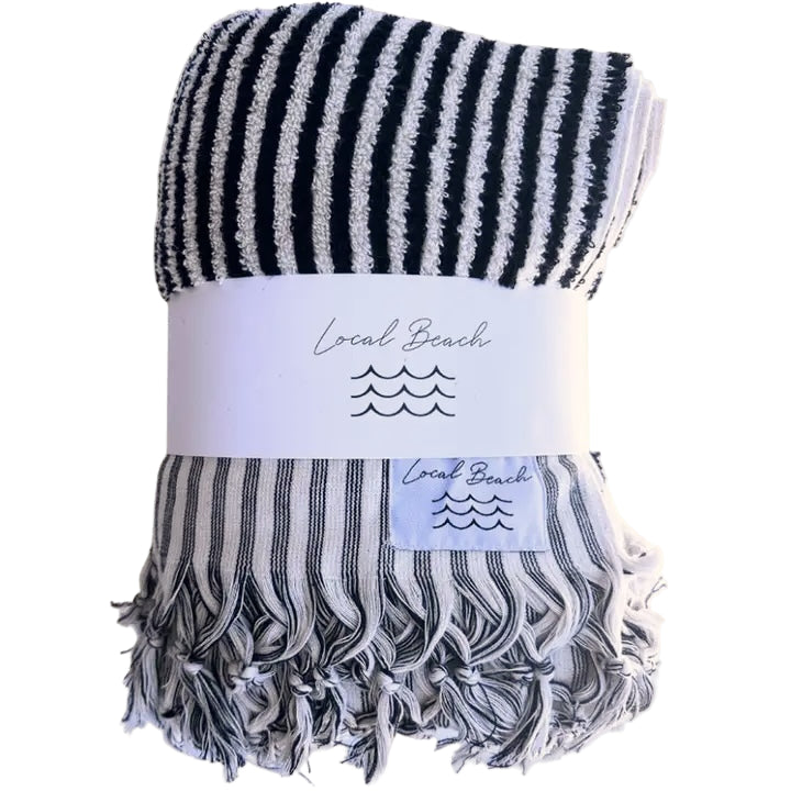 Striped towel with tassels and 'Local Beach' label on a white background
