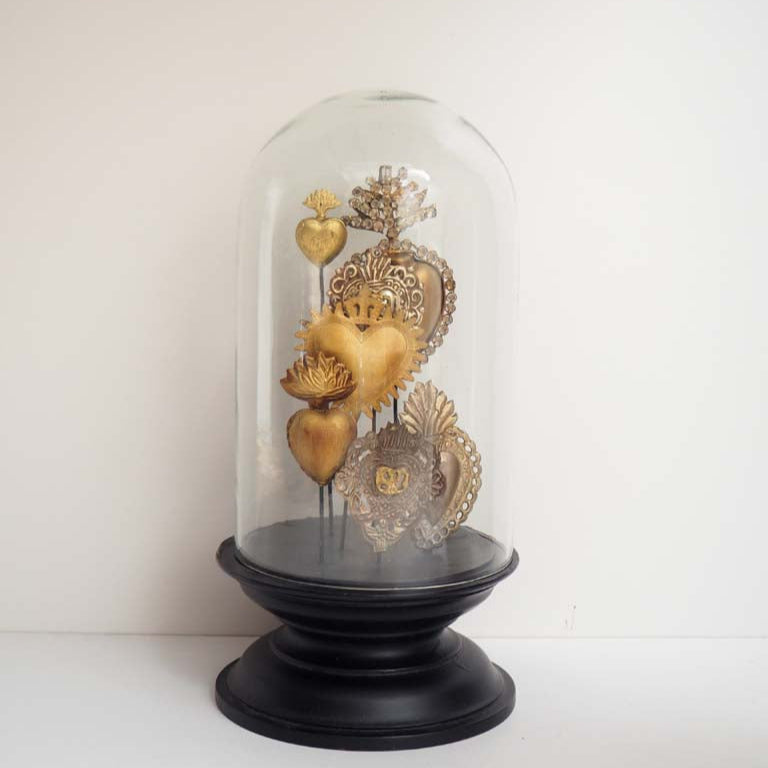 Decorative display of gold and silver hearts under a glass dome on a white background