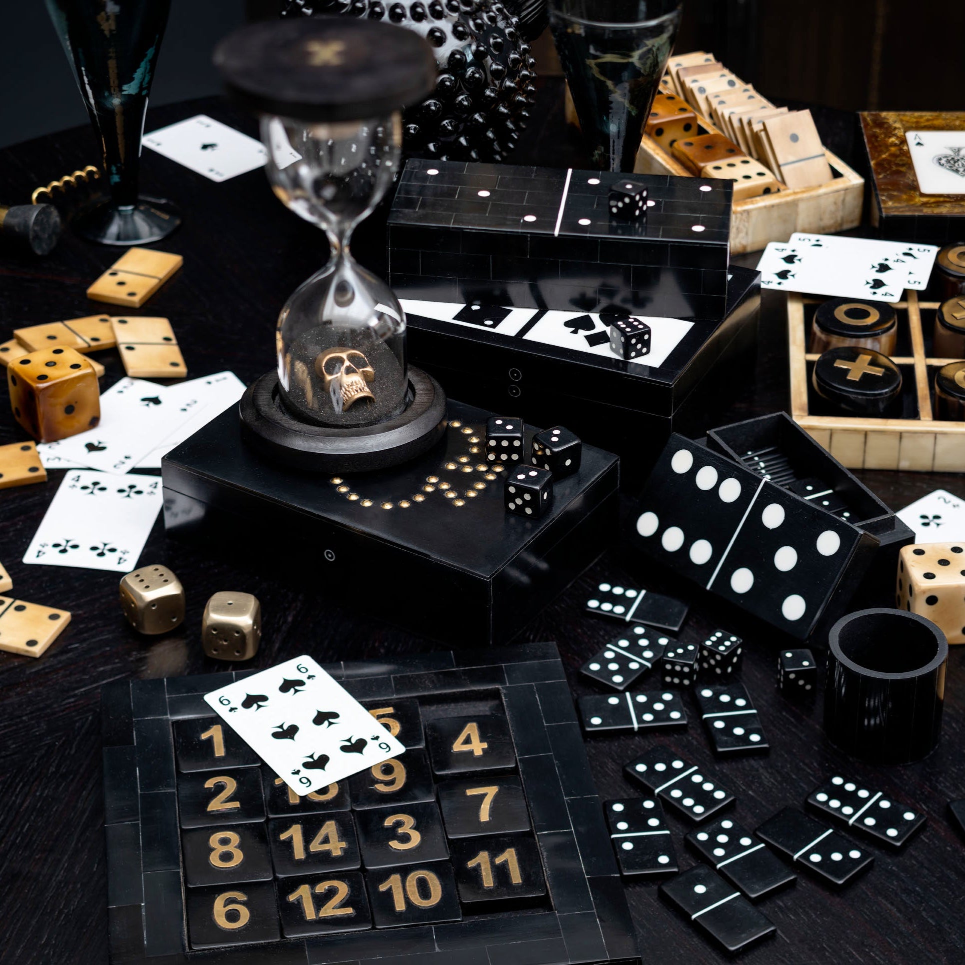 Assorted gambling items including cards, dice, and hourglass on a dark surface.