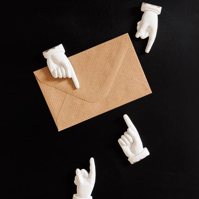 White hand-shaped letter openers on a black background with a brown envelope.