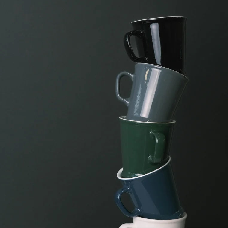 Stack of colorful mugs on a dark background