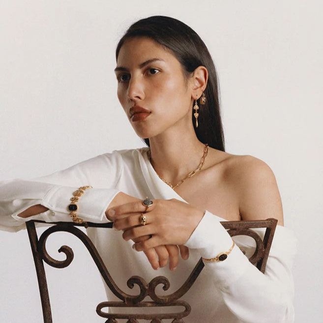 Woman sitting on a decorative chair against a plain background